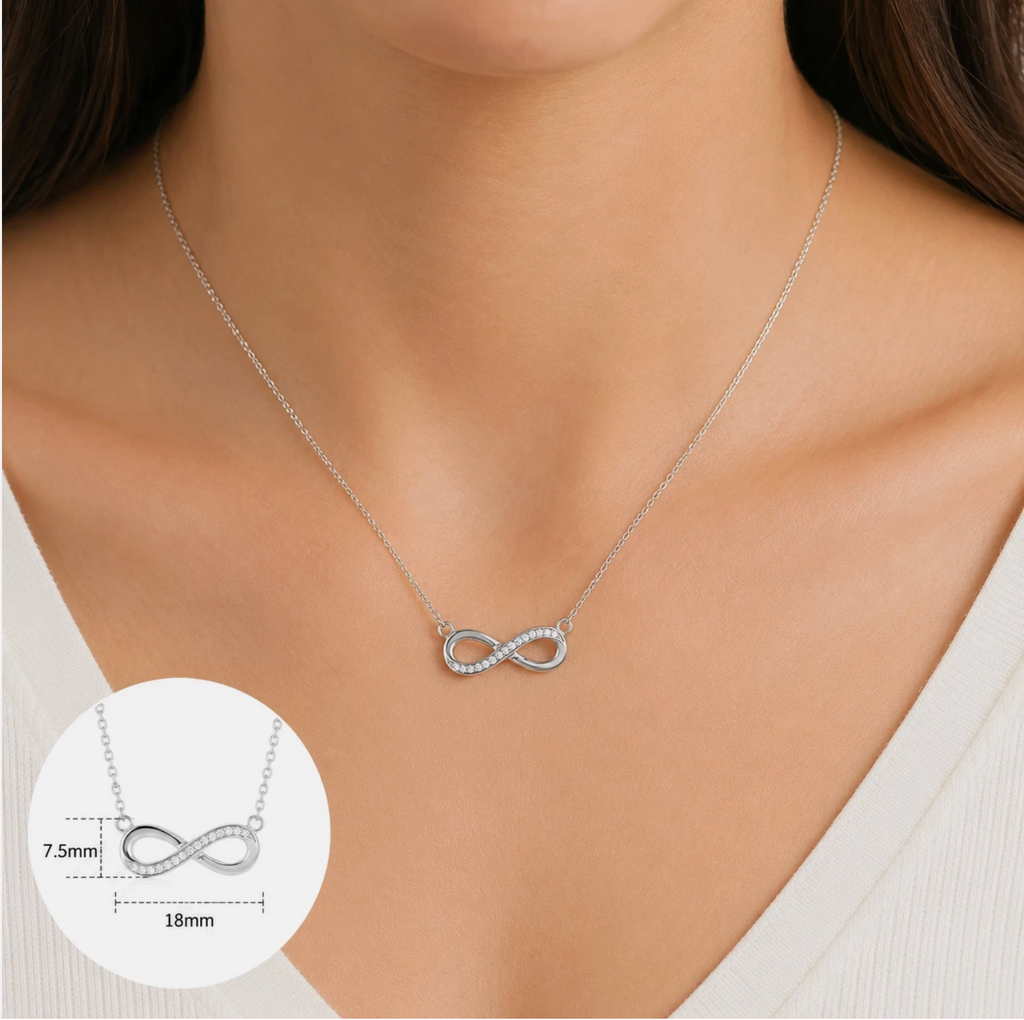 A woman wears a 14k gold over 925 sterling silver Infinity Necklace with cubic zirconia, featuring a pendant measuring 7.5mm high by 18mm wide. An inset shows a close-up of the necklace, paired with her white V-neck top.