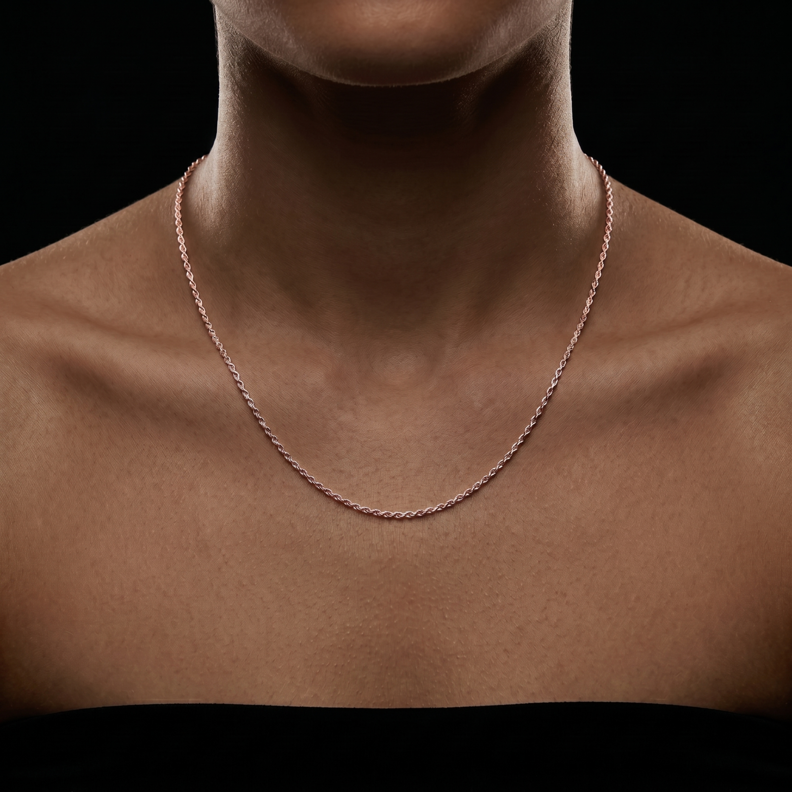 A close-up of a person’s neck and upper chest wearing a 1MM Solid 925 Rose Gold Sterling Silver Italian Diamond Cut Rope Chain Necklace against a black background. The strapless black top highlights the necklace's elegance and simplicity.
