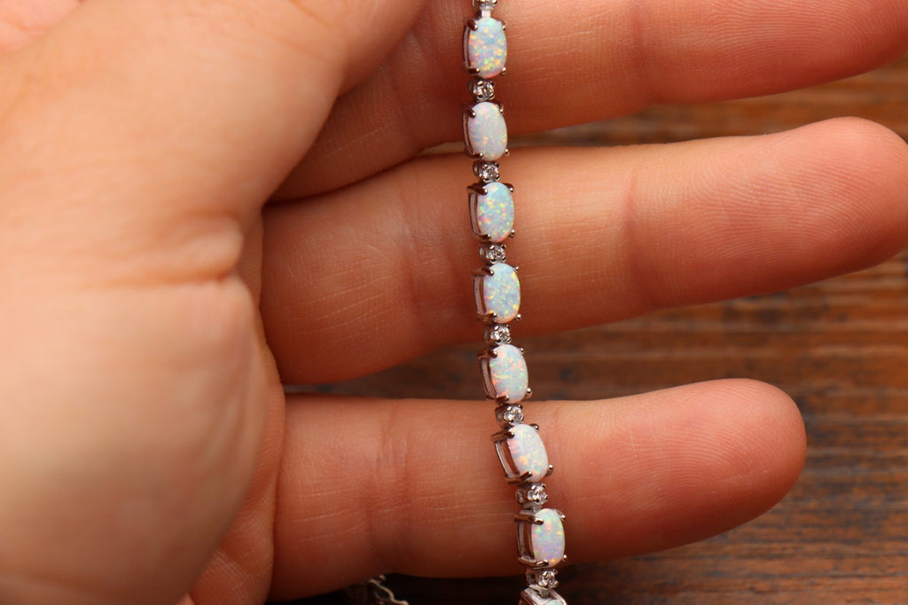 925 Sterling Silver White Lab White Opal Tennis Bracelet 7 Inch held by a hand