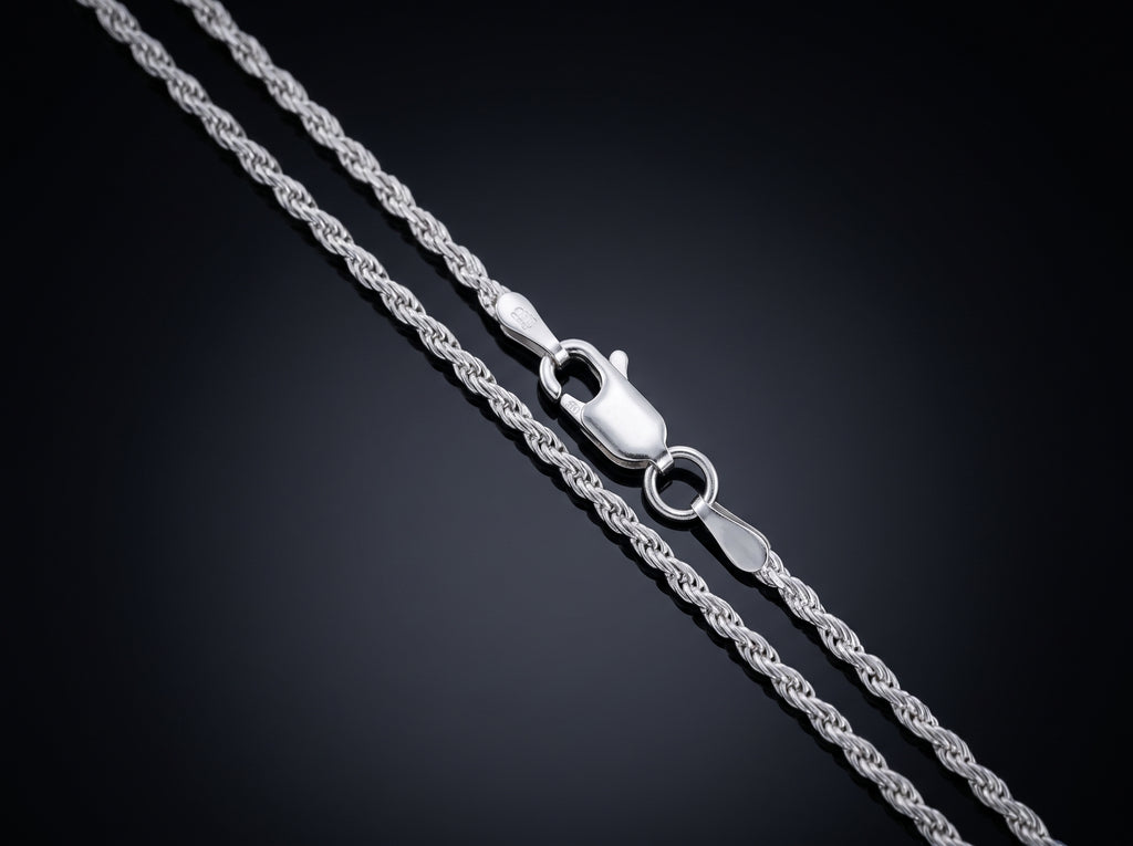 A close-up of a silver rope chain necklace with a lobster clasp, shown on a dark gradient background.
