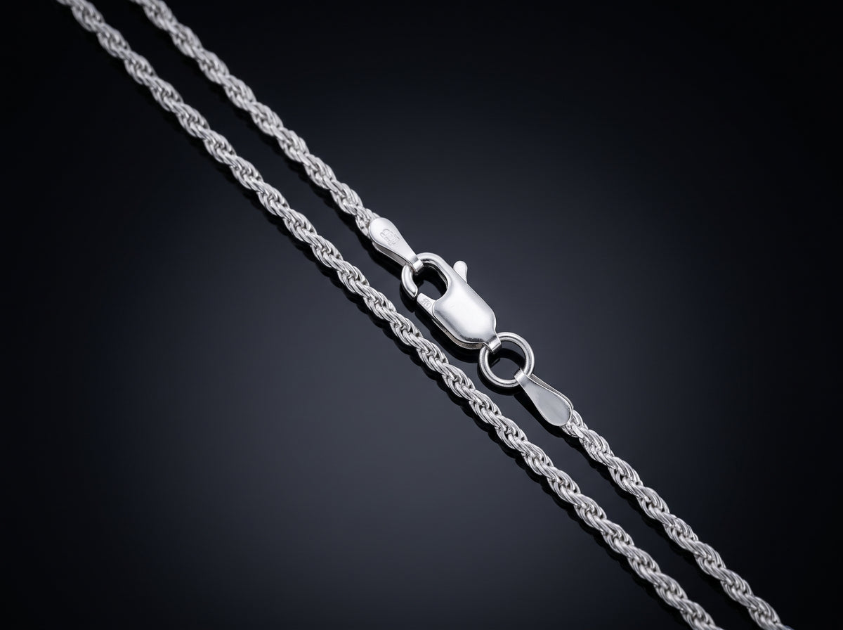 A close-up of a silver rope chain necklace with a lobster clasp, shown on a dark gradient background.