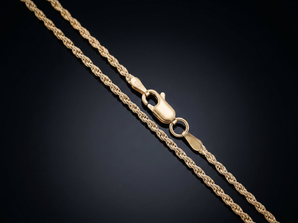 A close-up of a gold rope chain necklace with a lobster clasp, displayed diagonally on a dark gradient background.