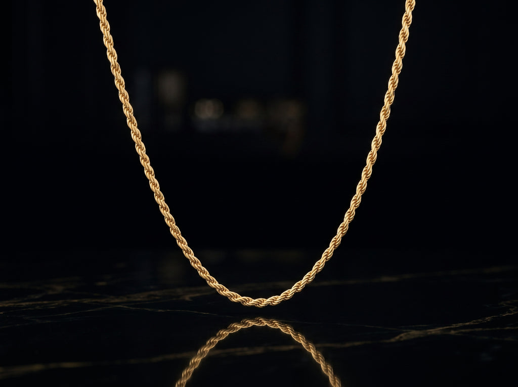 A twisted rope chain necklace in yellow gold, displayed in a U-shape against a dark, reflective black surface.