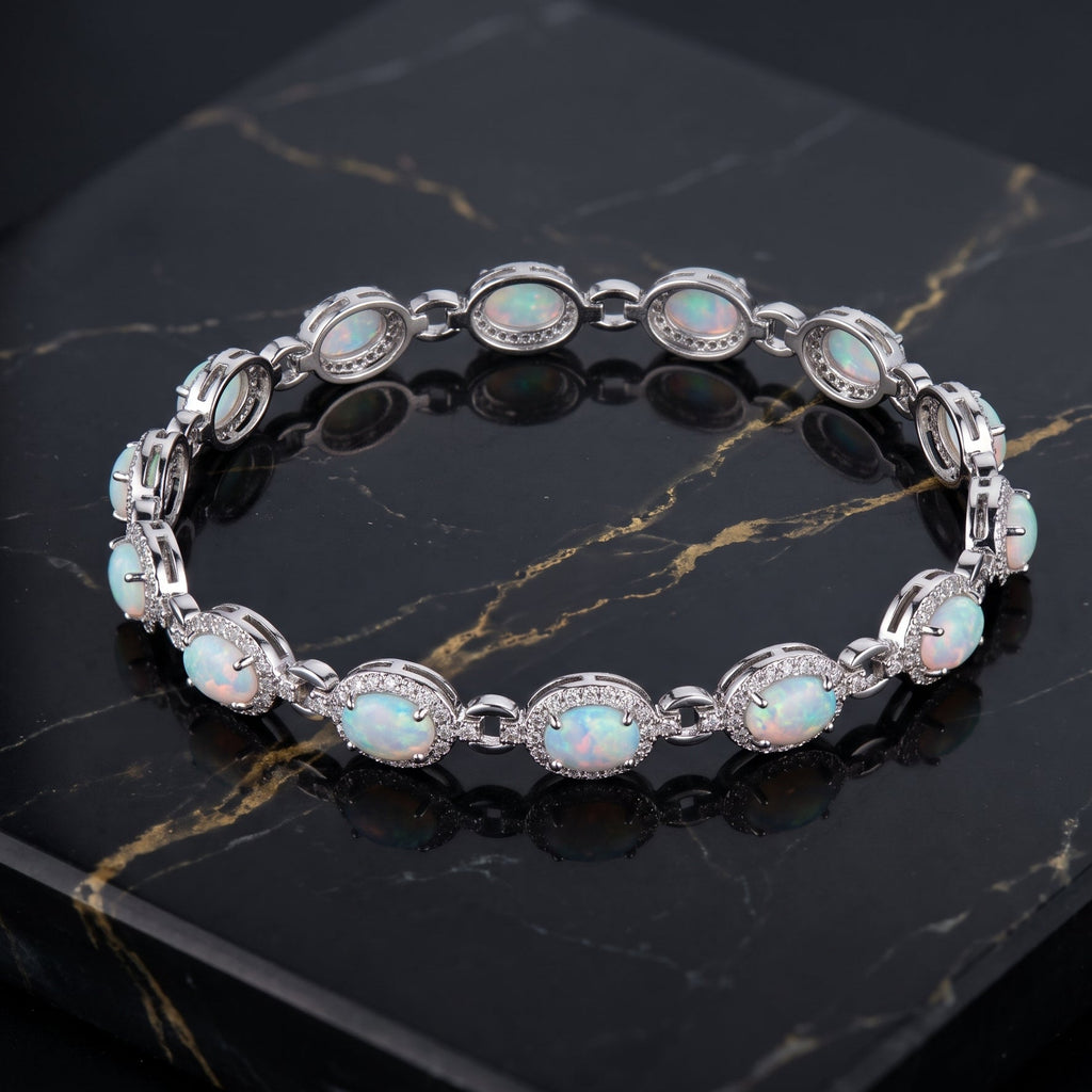 A silver-toned link bracelet featuring oval opal stones and small clear accent stones, displayed on a black marble surface.