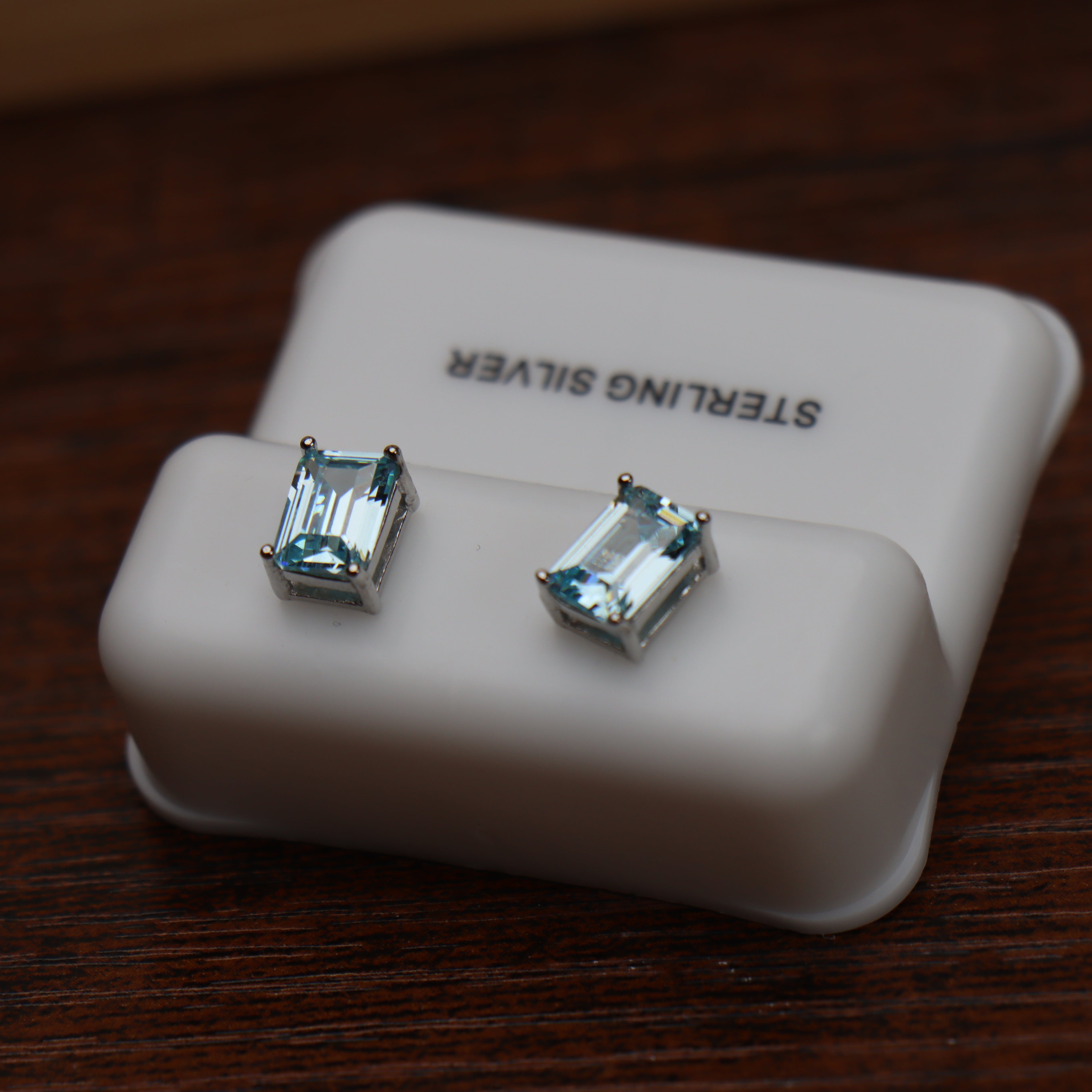 Emerald Cut Cz Earrings Blue Topaz 7x5mm 925 Sterling Silver on a white display stand