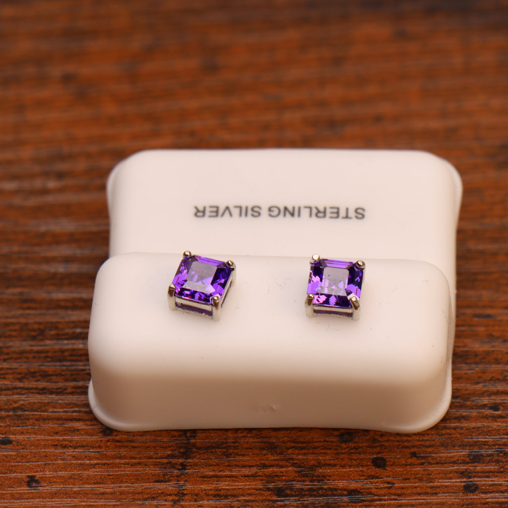 Purple CZ Earrings, Square Asscher Cut in 925 Sterling Silver, displayed on a white holder atop a wooden surface.