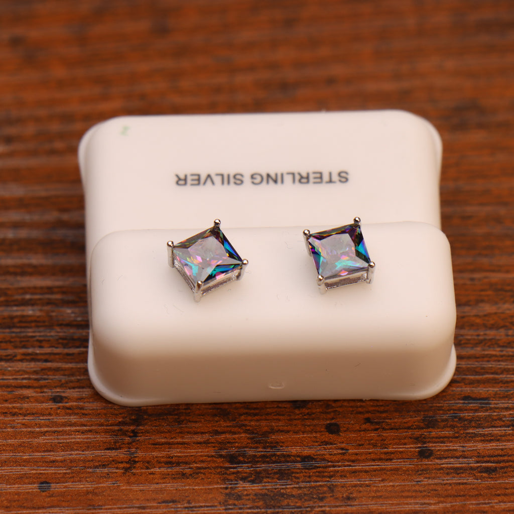 A pair of Mystic Topaz Cz square princess cut earrings in 925 sterling silver, displayed on a white padded holder labeled STERLING SILVER and placed on a wooden surface.
