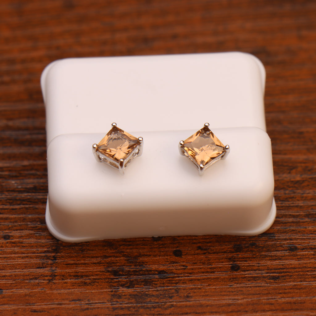 A pair of Morganite CZ square princess cut earrings in 925 sterling silver, displayed on a white jewelry holder atop a wooden surface.
