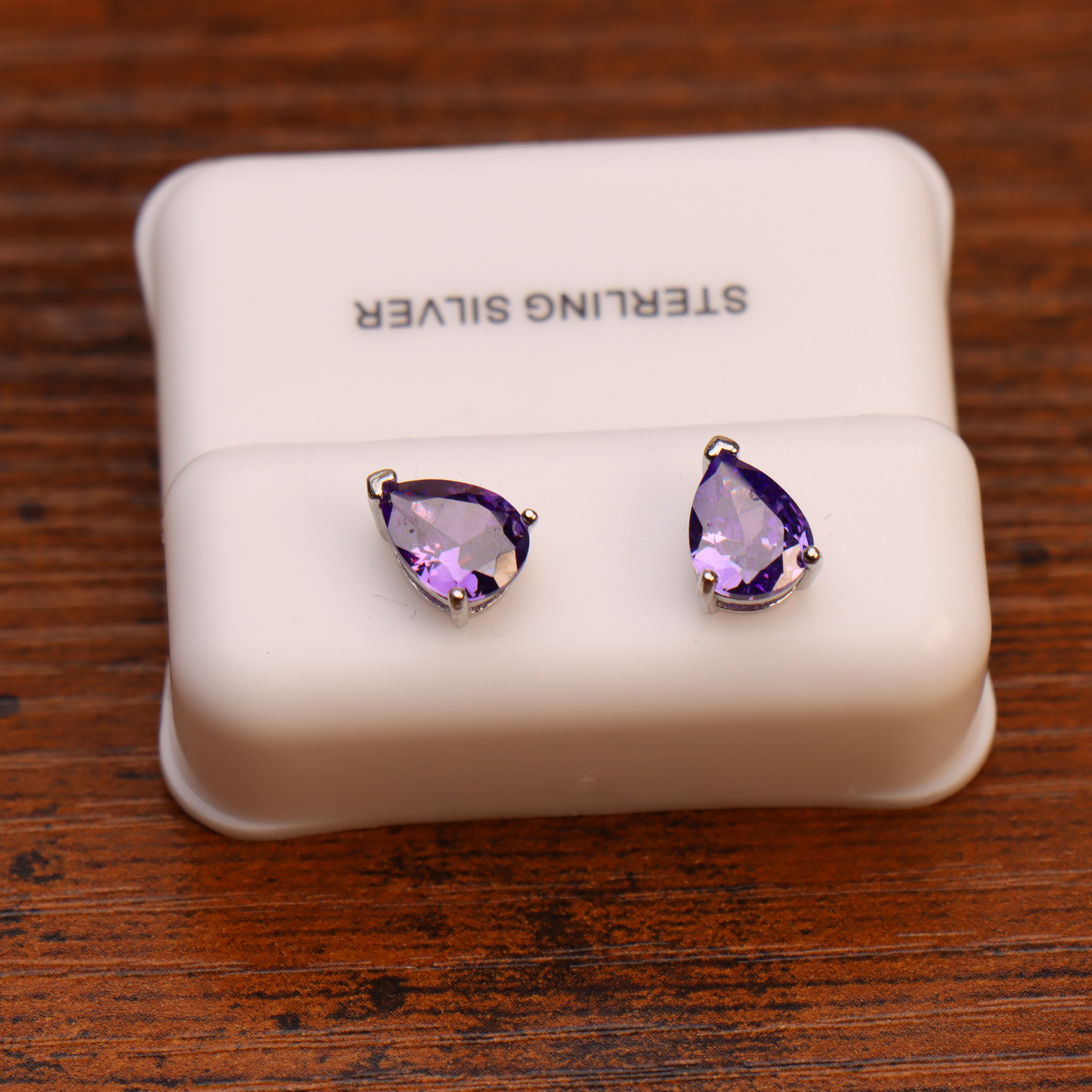 Pear shaped purple CZ earrings in 925 sterling silver with push backs on a white display stand