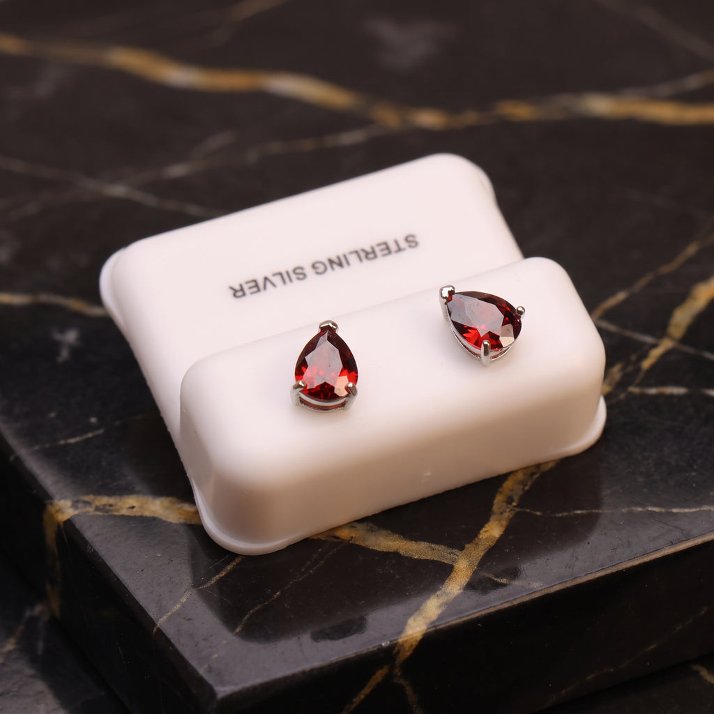 Pear shaped garnet CZ earrings in 925 sterling silver with push backs on a white display stand