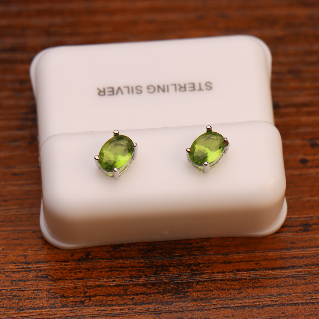 Oval peridot CZ earrings in 925 sterling silver settings on a white display stand