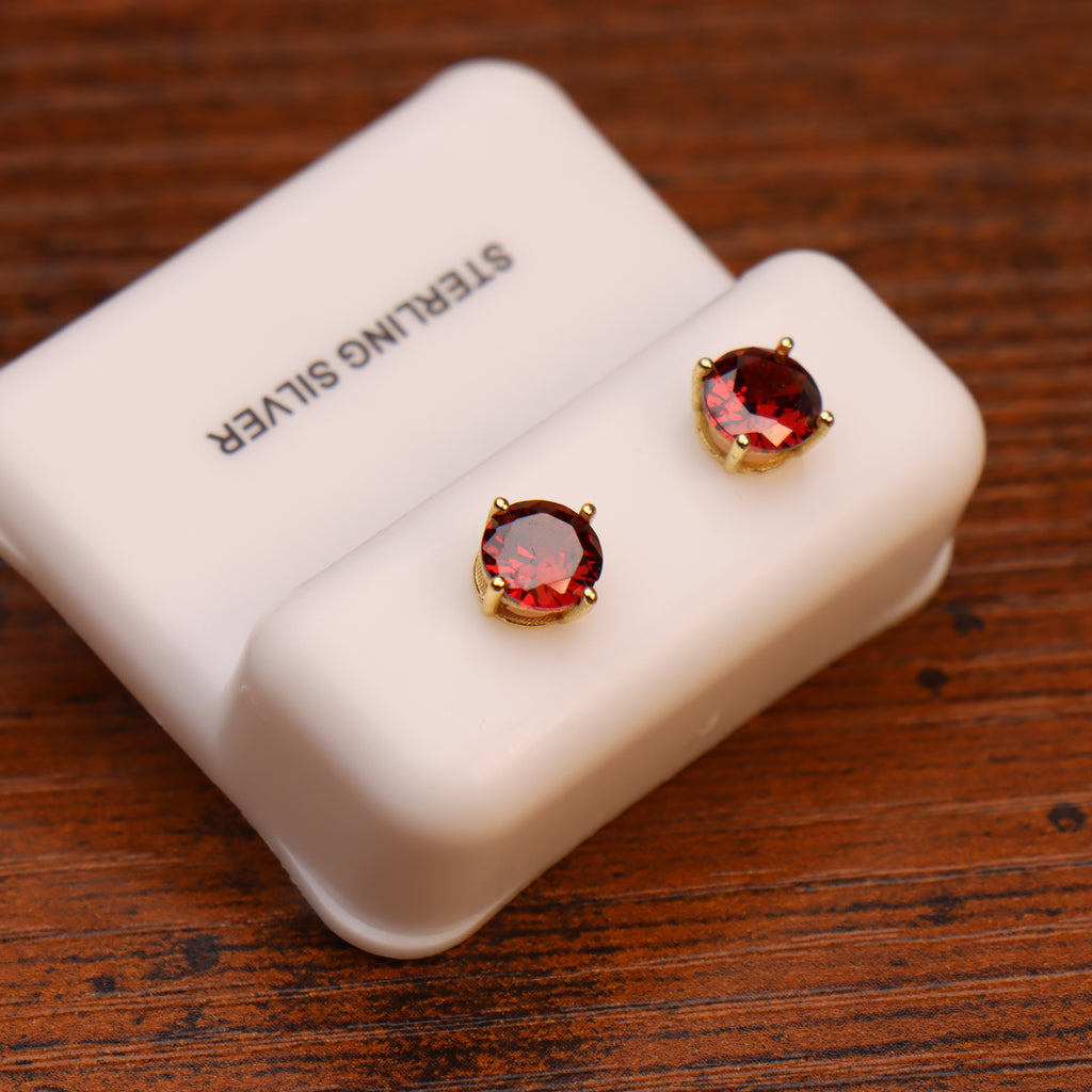 Ruby red round CZ stud earrings in 14k gold over 925 sterling silver on a white display card