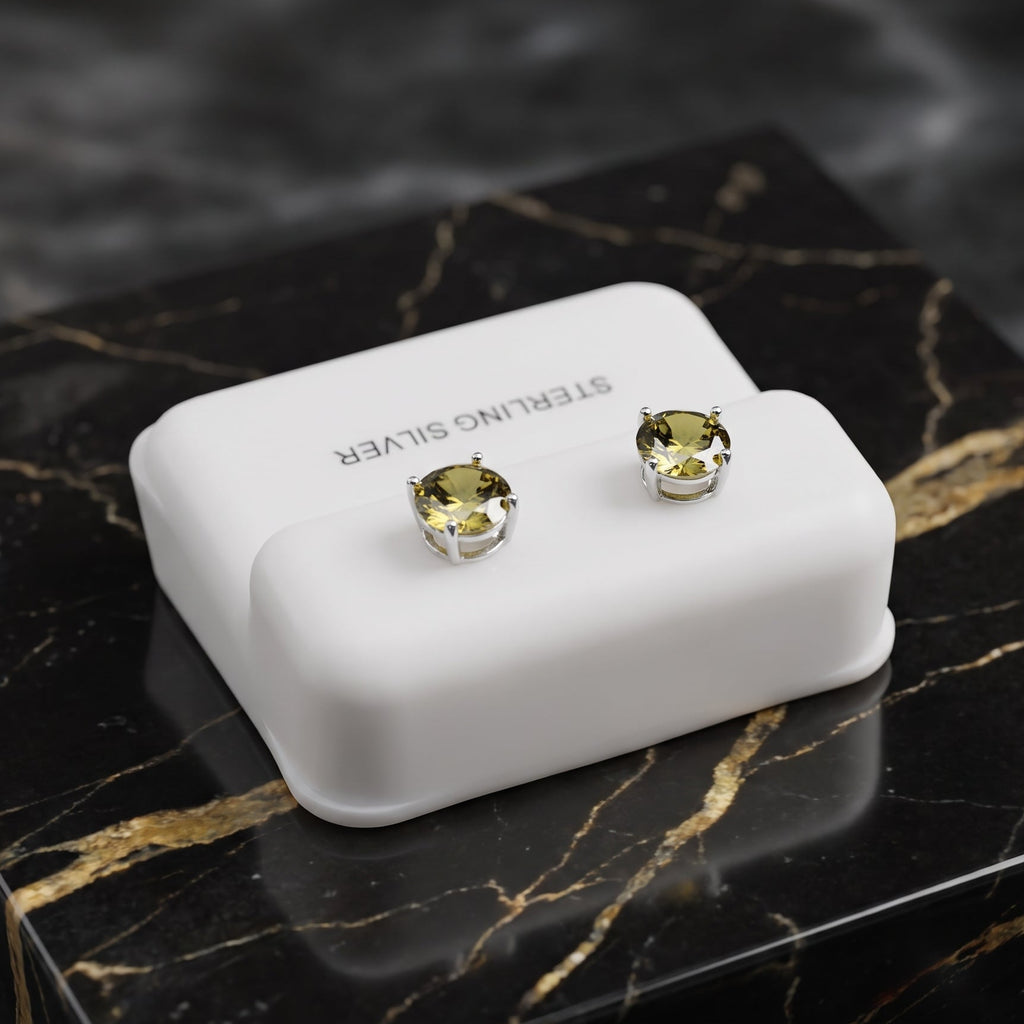 Sterling silver stud earrings with round yellow-green gemstones, displayed on a white rectangular jewelry stand placed on a black marble box.
