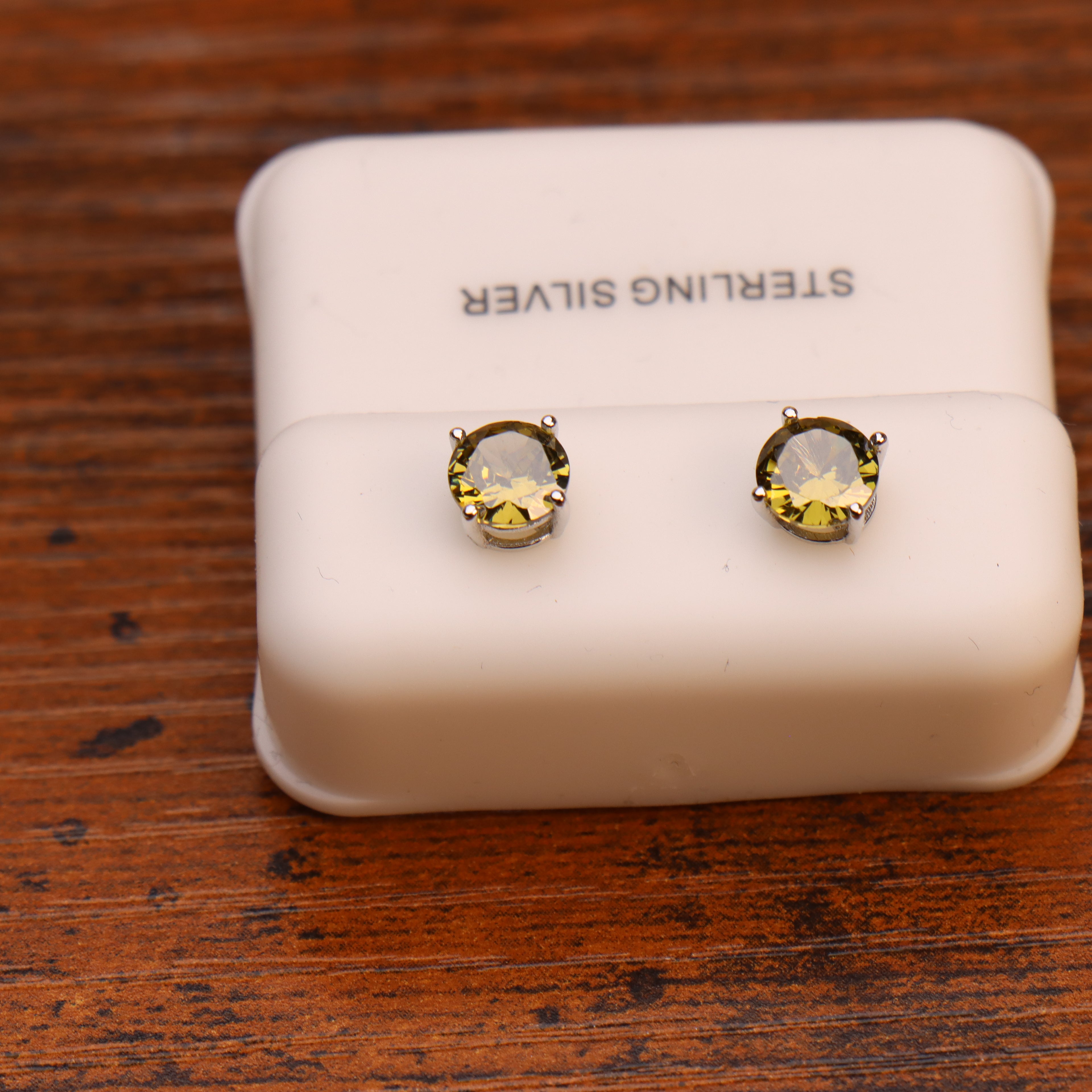 Dark peridot round 6mm cubic zirconia stud earrings set in 925 sterling silver on a white display stand