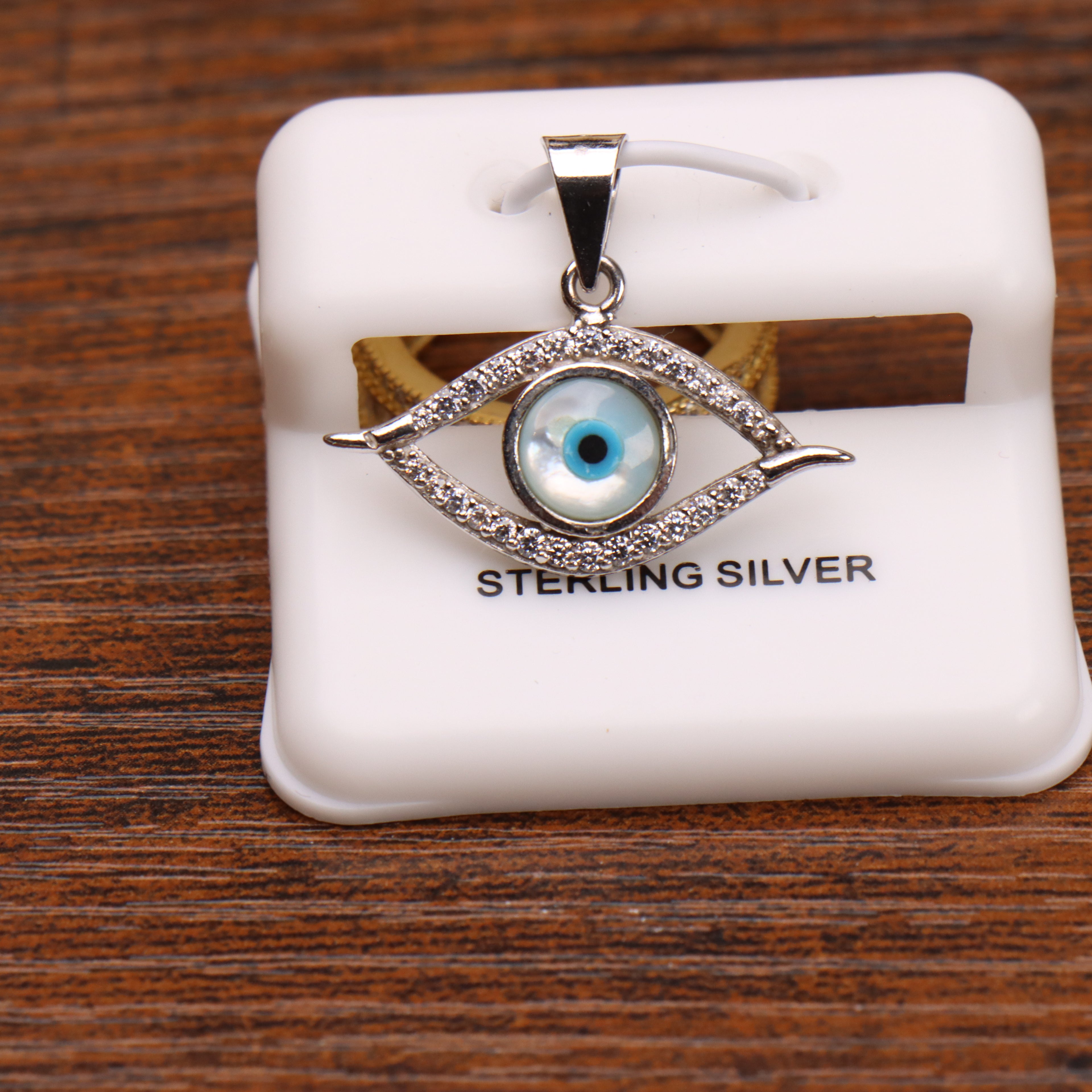 Evil eye elongated pendant charm in sterling silver with pave stones on a white display stand