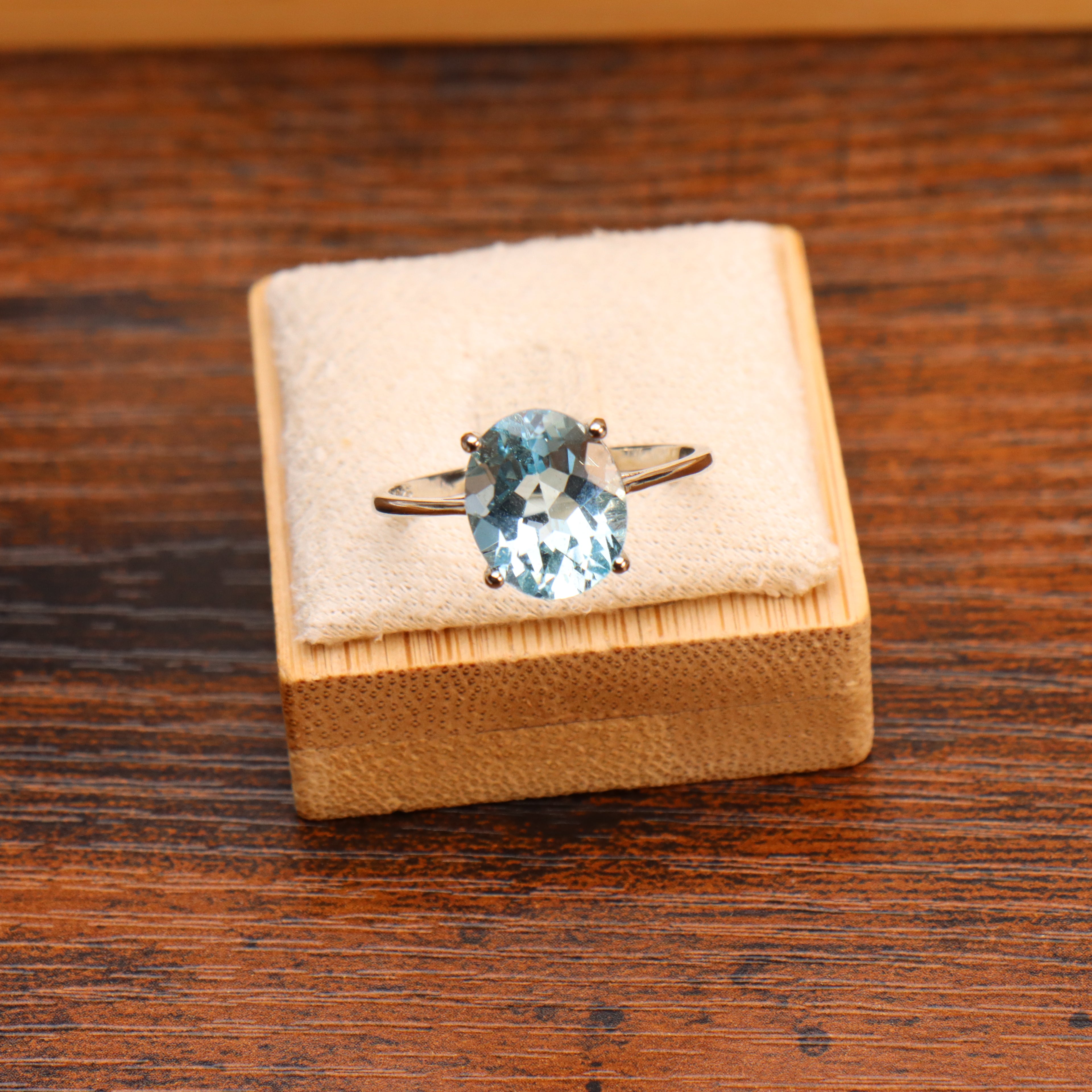 Oval cut blue topaz ring in 925 sterling silver on a beige display cushion