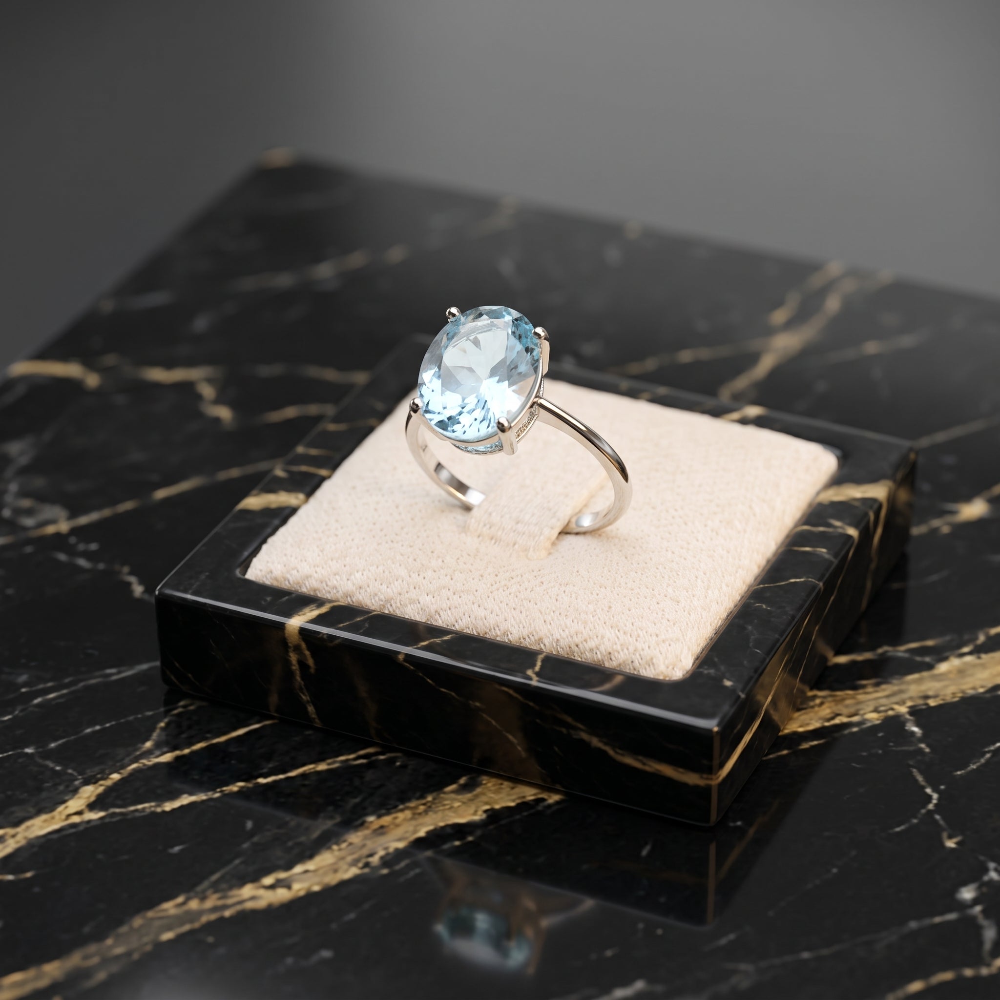 Blue topaz oval cut ring in 925 sterling silver on a beige velvet display stand