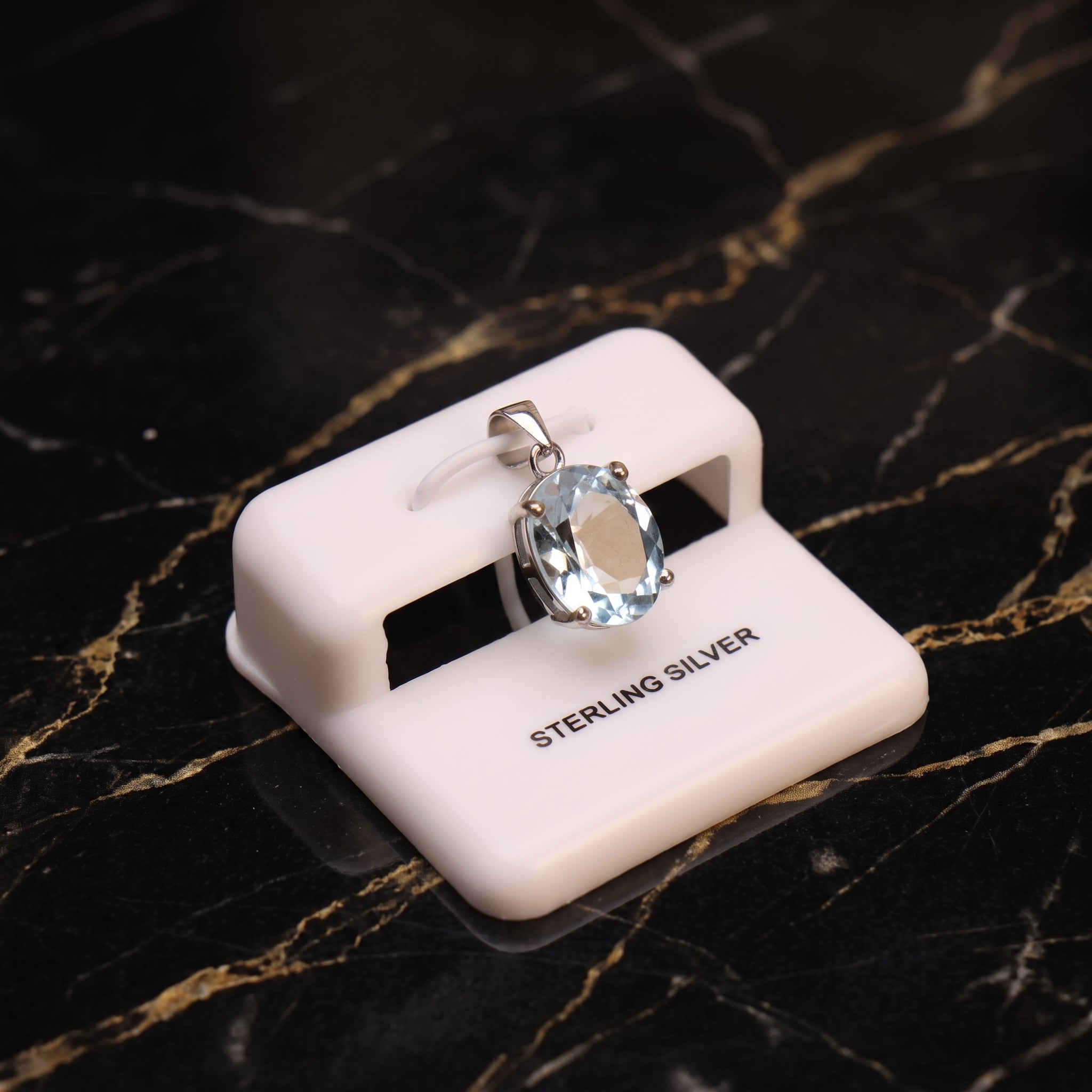 Blue topaz oval semi precious natural pendant in 925 sterling silver on a white display stand