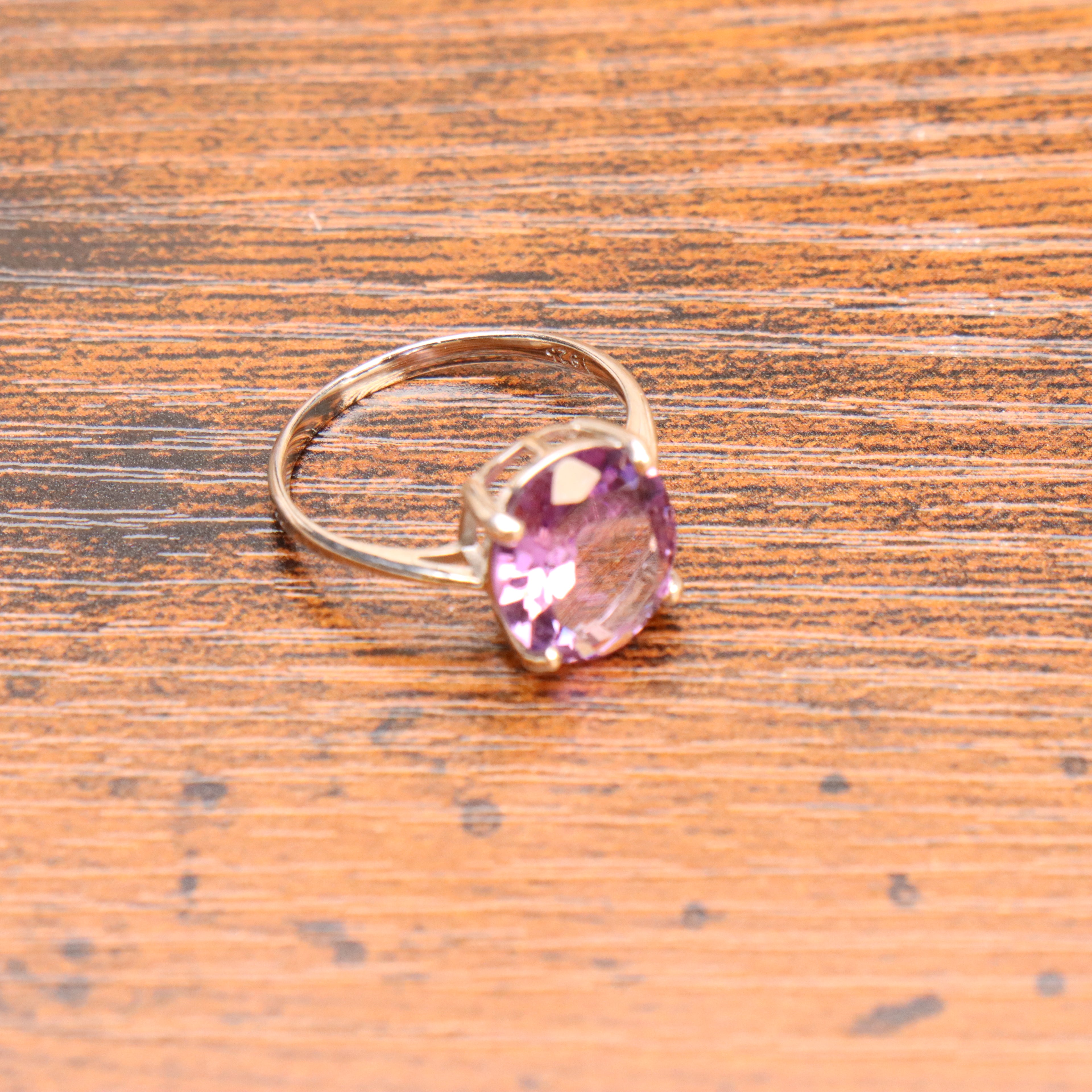 Amethyst purple semi precious natural ring in 925 sterling silver with an oval cut stone on a wood grain surface