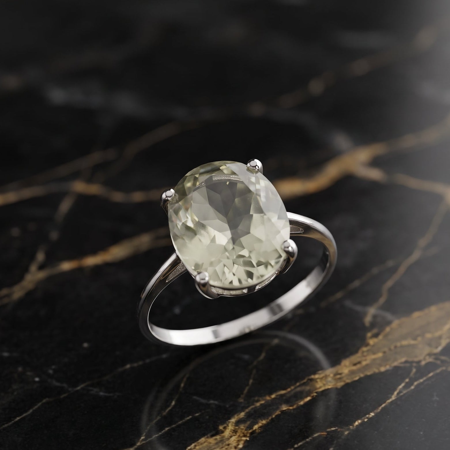 A silver ring with a large oval-cut pale green gemstone, displayed on a black and gold veined marble surface. GREEN AMethyst