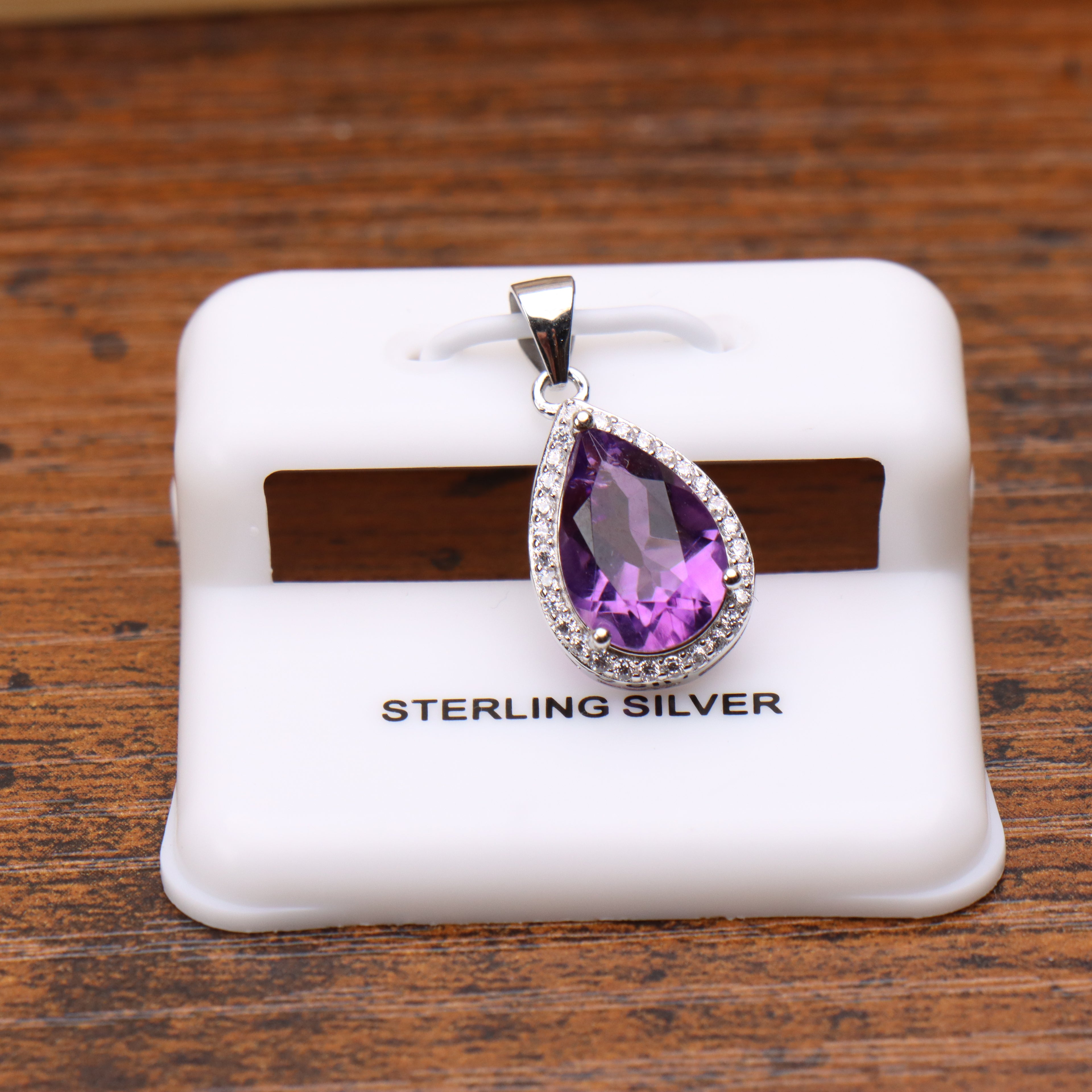 Amethyst pear shaped pendant with a cubic zirconia halo set in 925 sterling silver on a white display stand