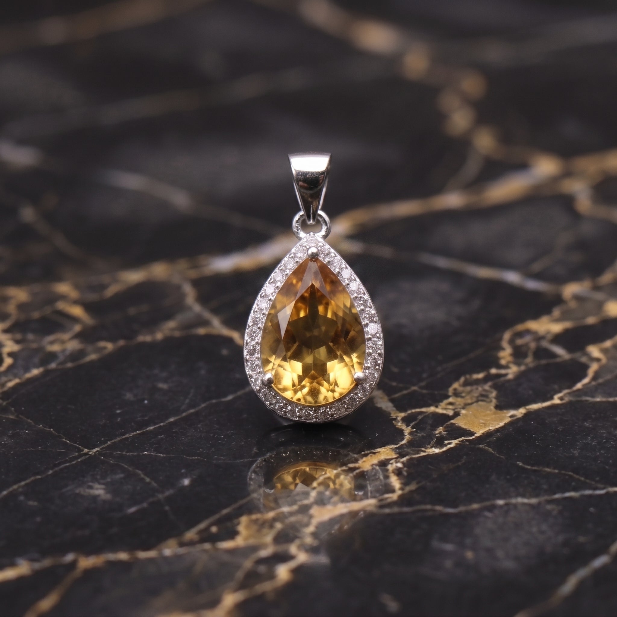 Citrine pear pendant with halo of CZ stones in 925 sterling silver on black marble surface