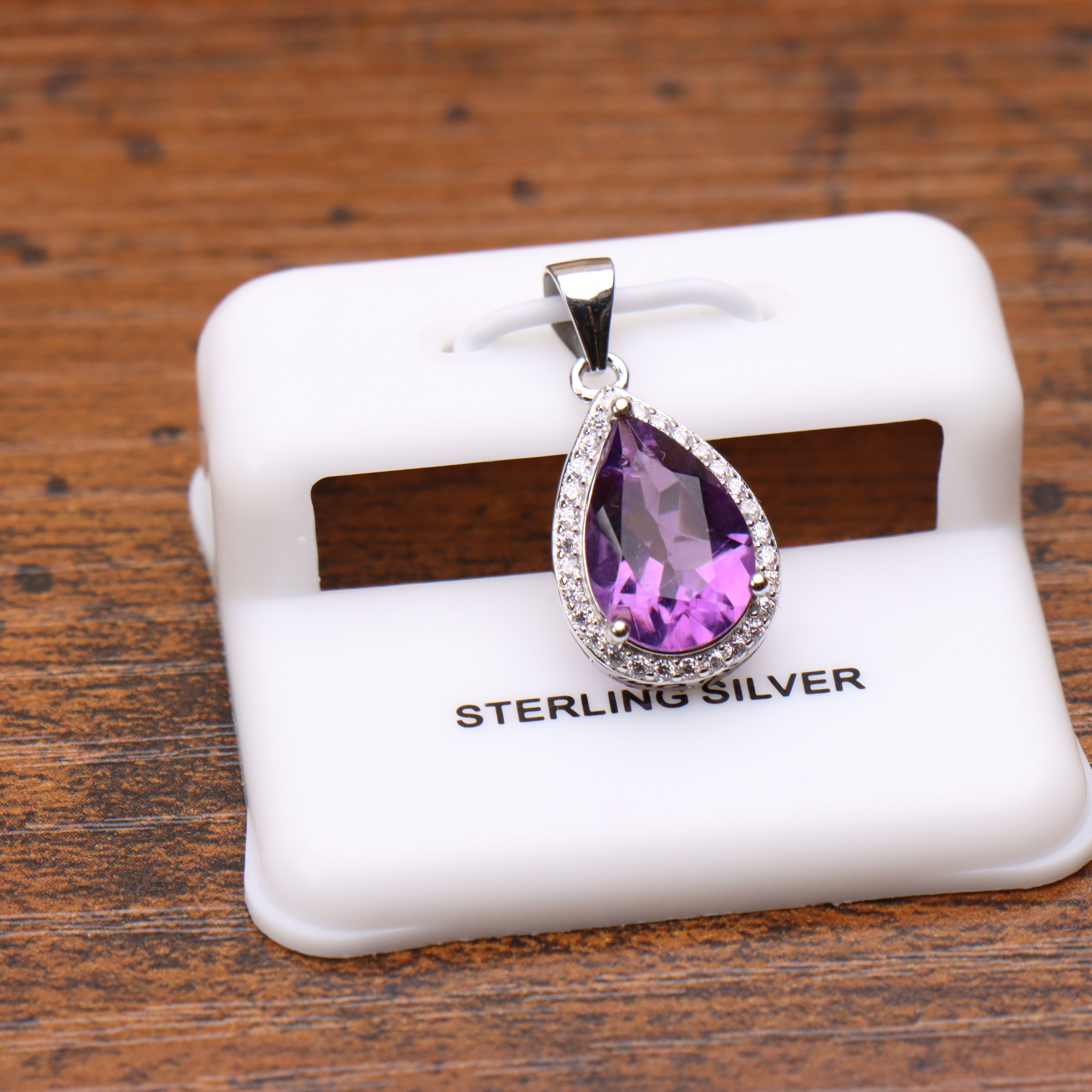 Amethyst pear shaped pendant with cz halo in 925 sterling silver on a white display stand