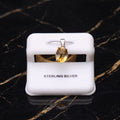 Sterling silver pendant with an oval-cut yellow gemstone, displayed on a white jewelry stand over a black marble background.