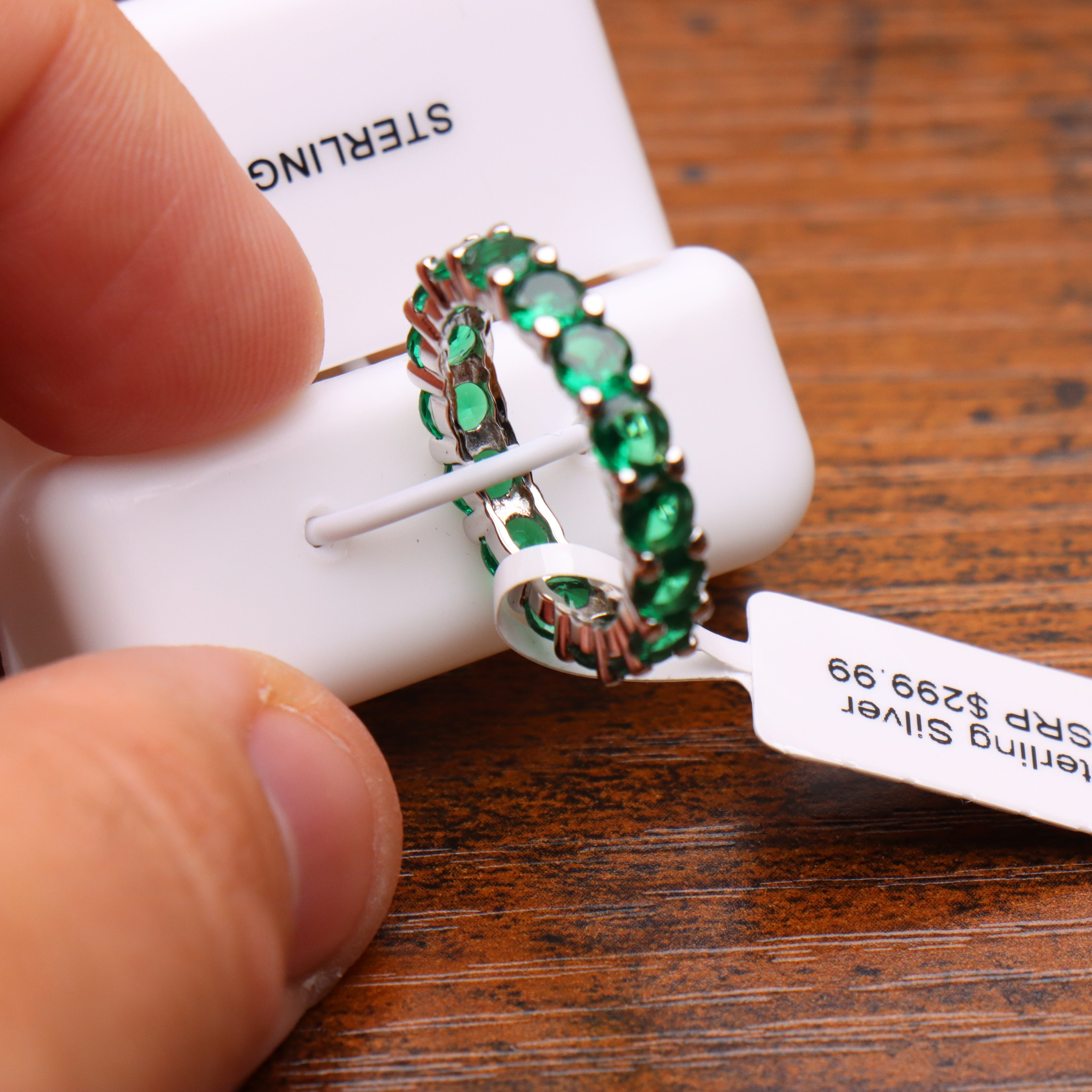 Green CZ eternity band ring in 925 sterling silver with round cut stones on a display stand