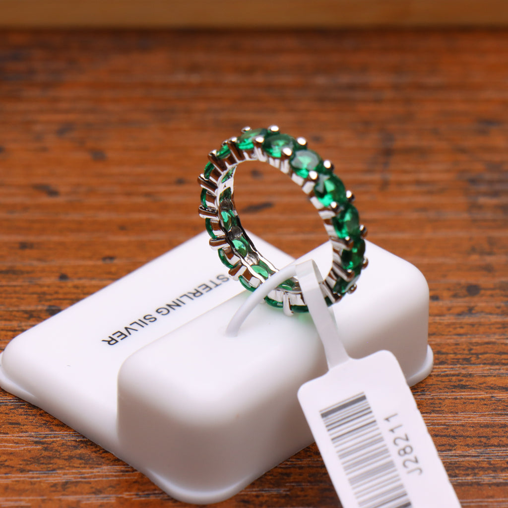 Green CZ eternity band ring in 925 sterling silver with round cut stones on a display stand