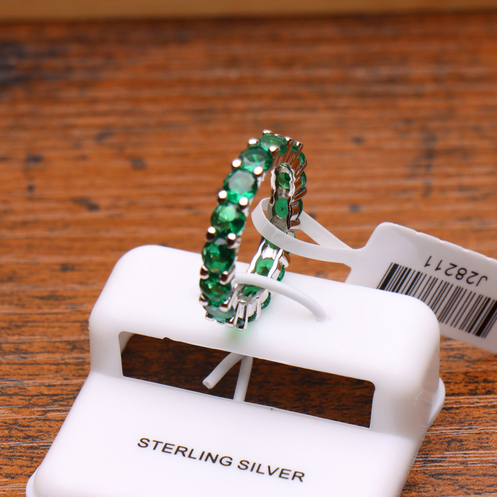 Green CZ eternity band ring in 925 sterling silver with round cut stones on a white display stand