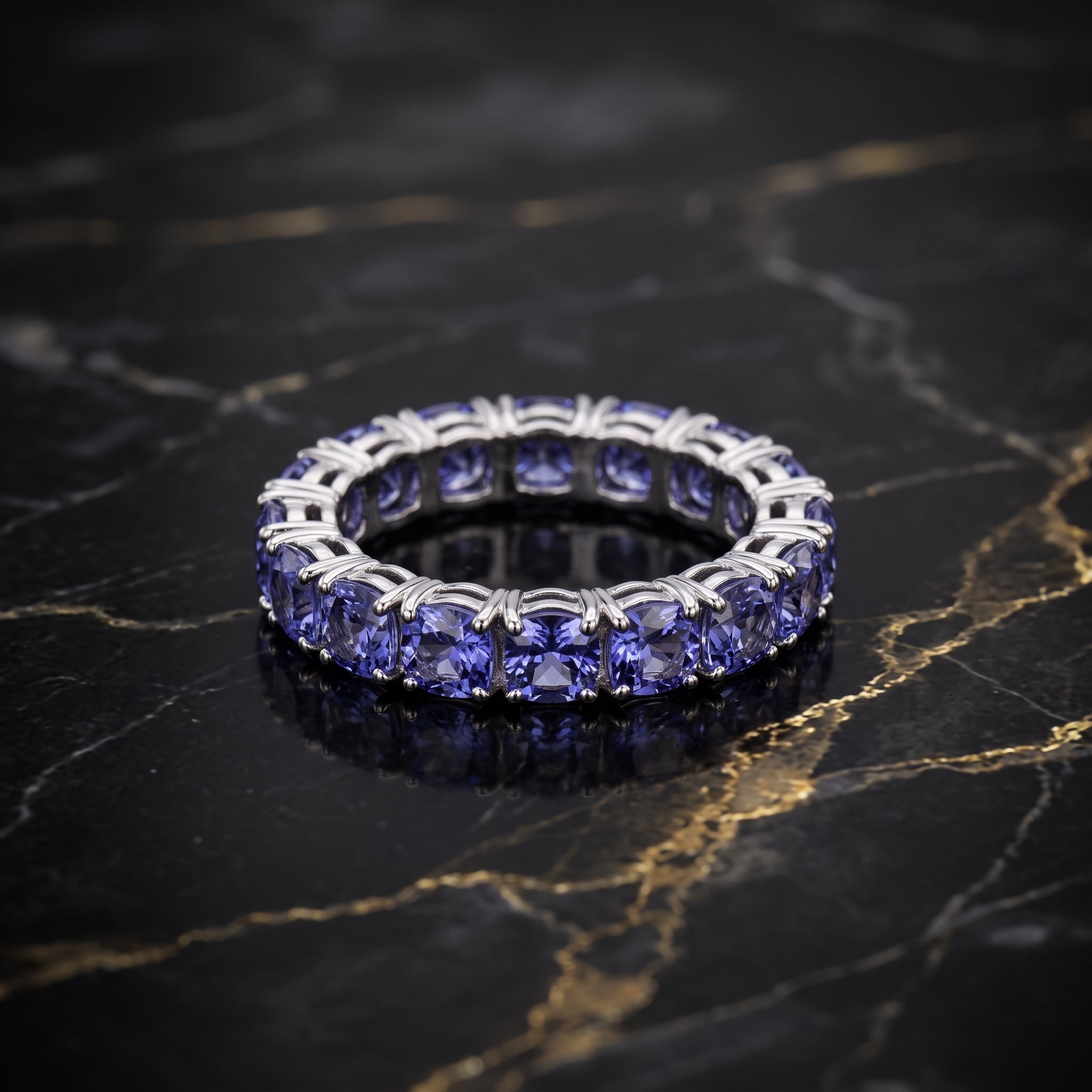 Tanzanite color round cut CZ eternity band in sterling silver on black marble surface