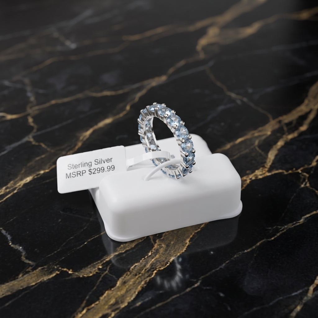 A sterling silver eternity band ring with clear stones, displayed on a white plastic stand with a price tag that reads 'Sterling Silver MSRP $299.99'.