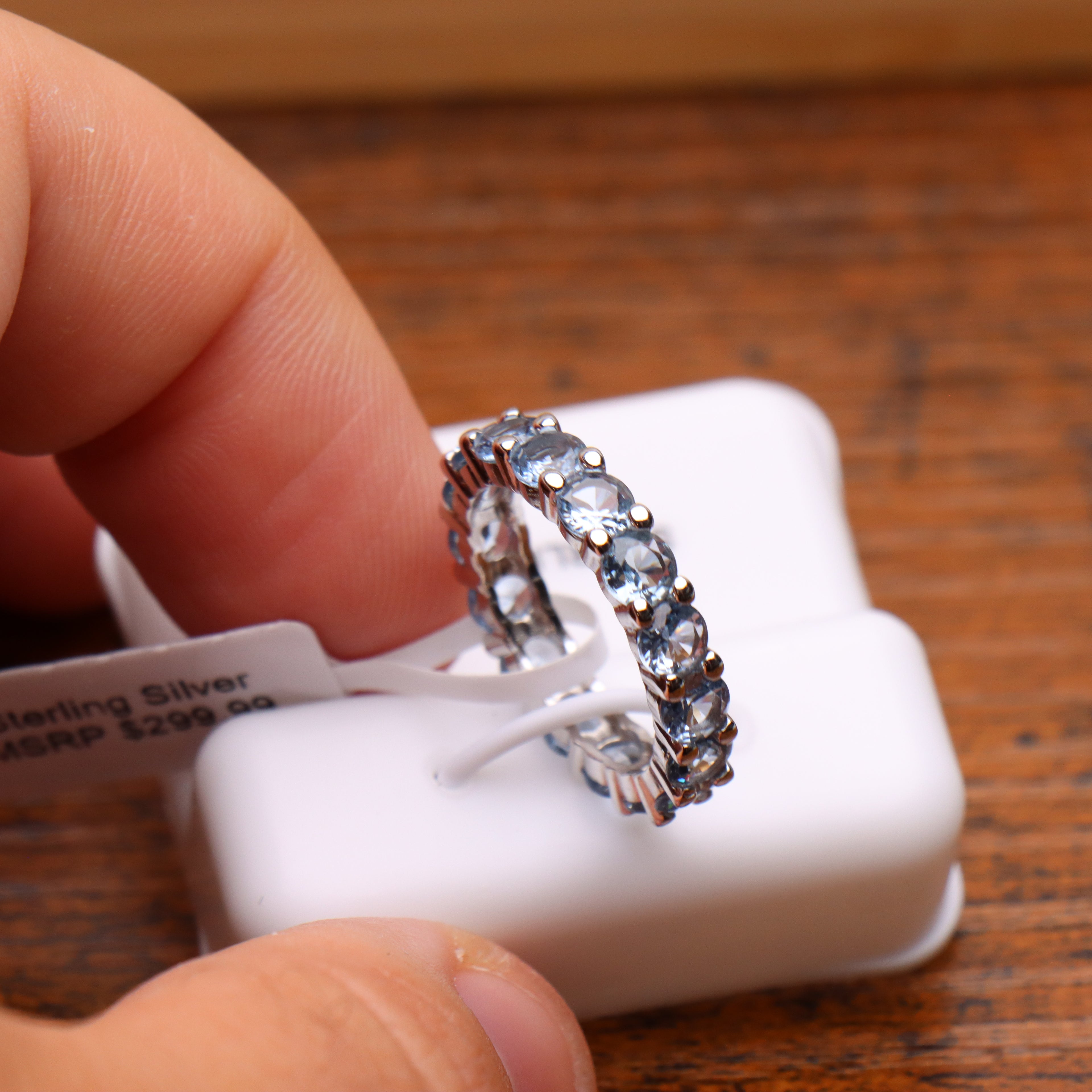 Light blue CZ eternity band ring in 925 sterling silver with round cut stones on a white display stand