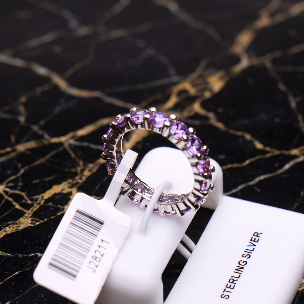 Purple CZ eternity band ring in 925 sterling silver with round cut stones on a display stand