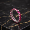 Magenta ruby eternity band ring in 925 sterling silver on a black marble surface