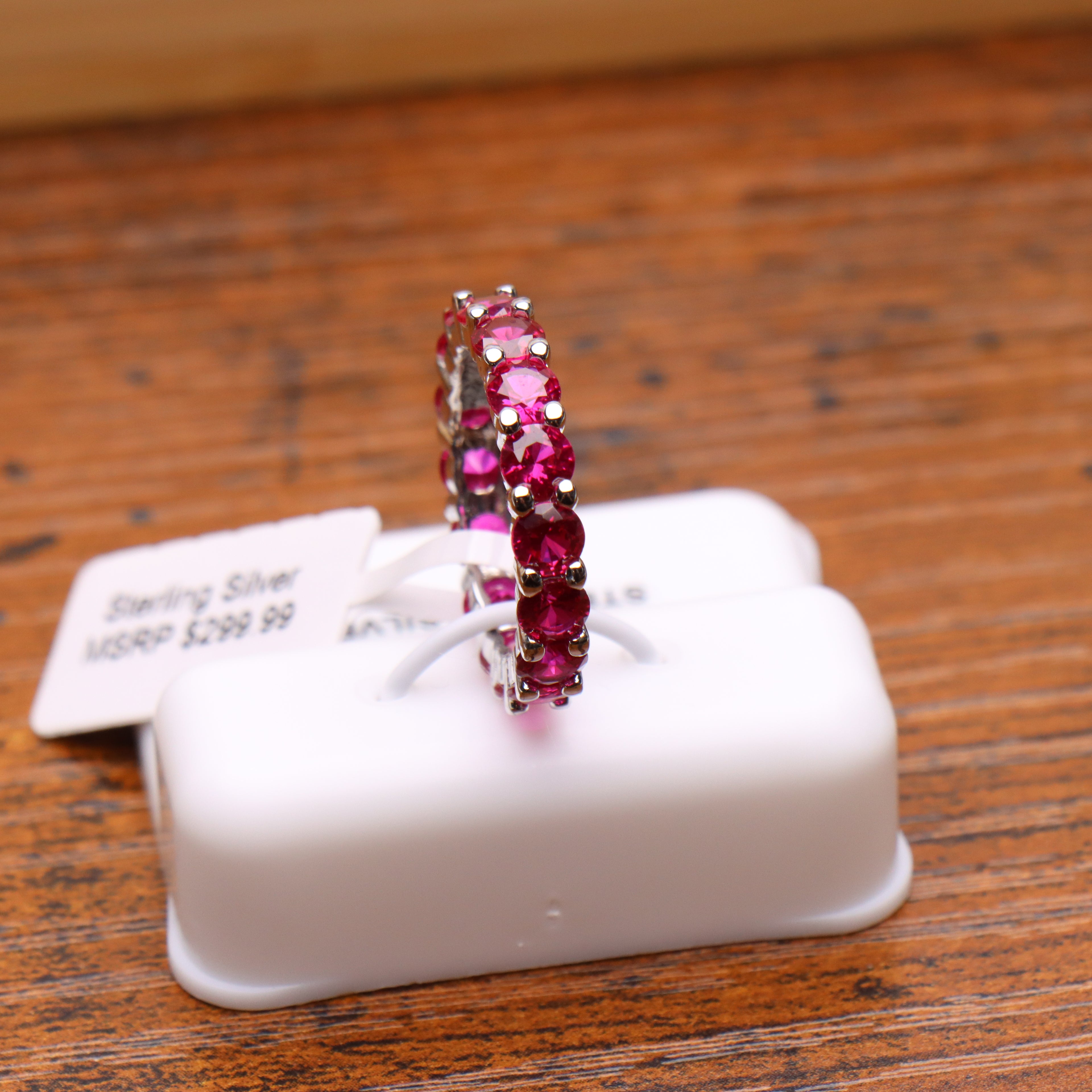 Magenta ruby CZ eternity band ring in 925 sterling silver on a white display stand